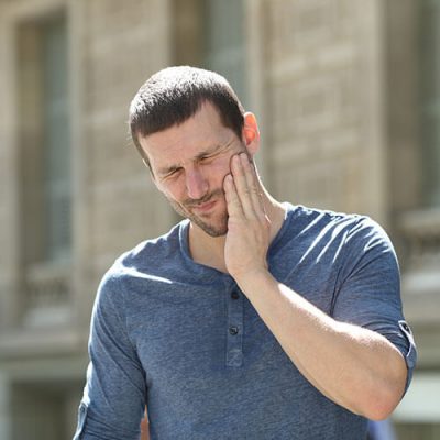 Man touching cheek with TMJ pain
